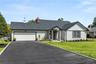 View of front of home with driveway, a front lawn, a garage, a shingled roof, and a chimney