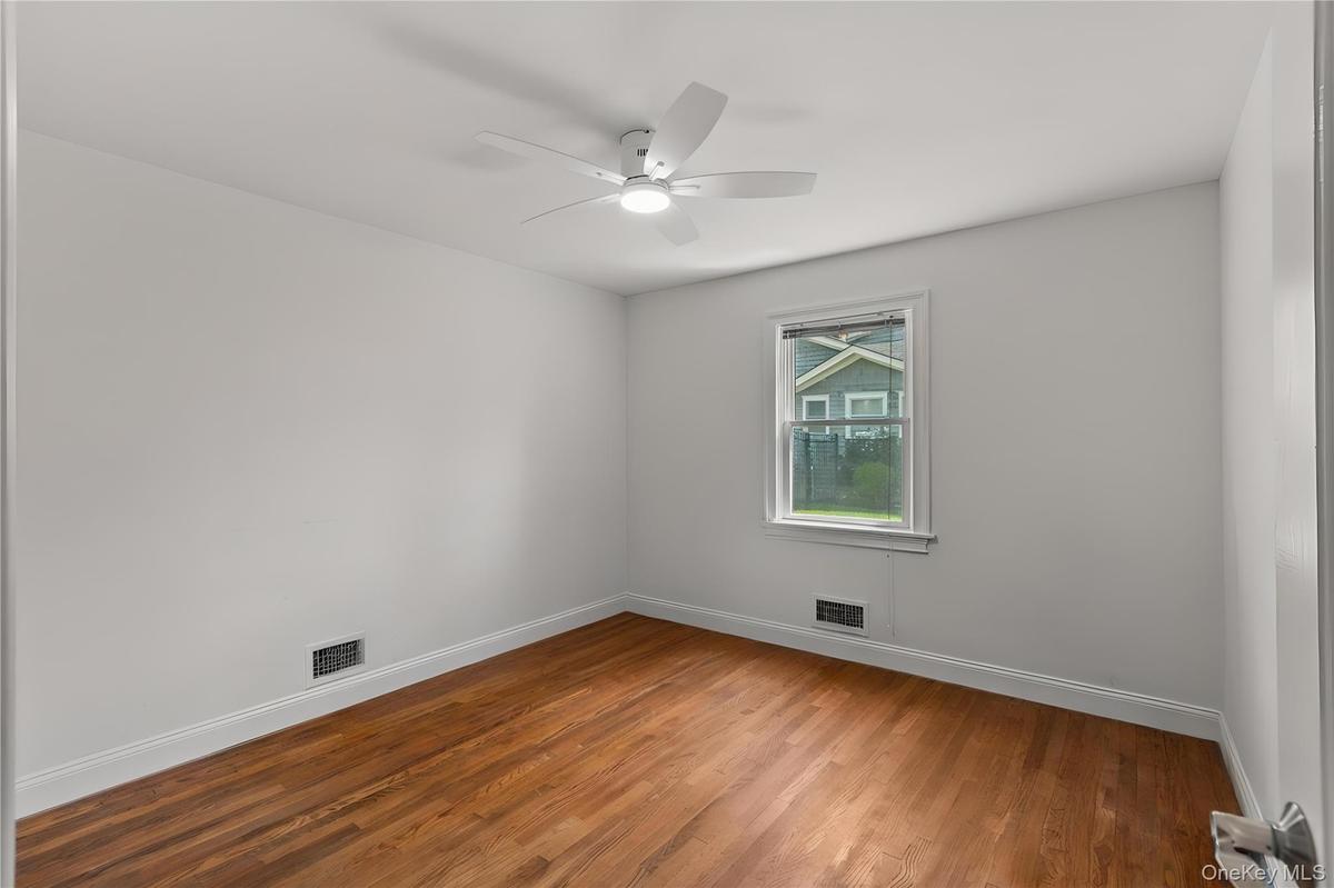 Empty room with wood finished floors and a ceiling fan