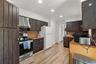 Kitchen with dark brown cabinetry, crown molding, electric range, ventilation hood, and tasteful backsplash