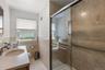 Full bathroom with vanity, a shower stall, tile walls, light tile patterned floors, and a wainscoted wall