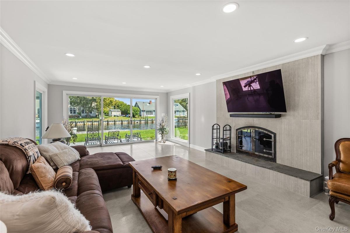 Living room with ornamental molding, recessed lighting, and a fireplace