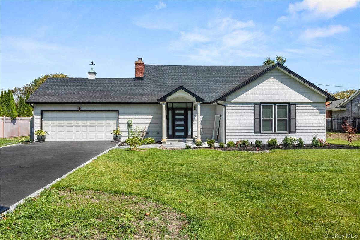View of front of home featuring a chimney, a garage, driveway, and roof with shingles