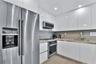 Kitchen featuring high-gloss white cabinetry, solid surface countertops, recessed lighting, and stainless steel appliances including a built-in oven, 