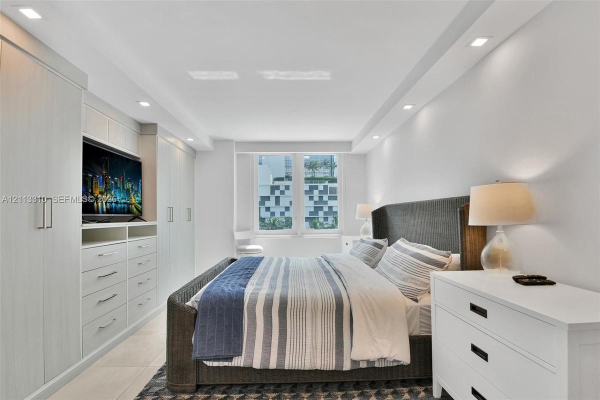 Built-in custom cabinetry with integrated shelving, recessed ceiling lighting, tray ceiling detail, large-format tile flooring, and oversized windows