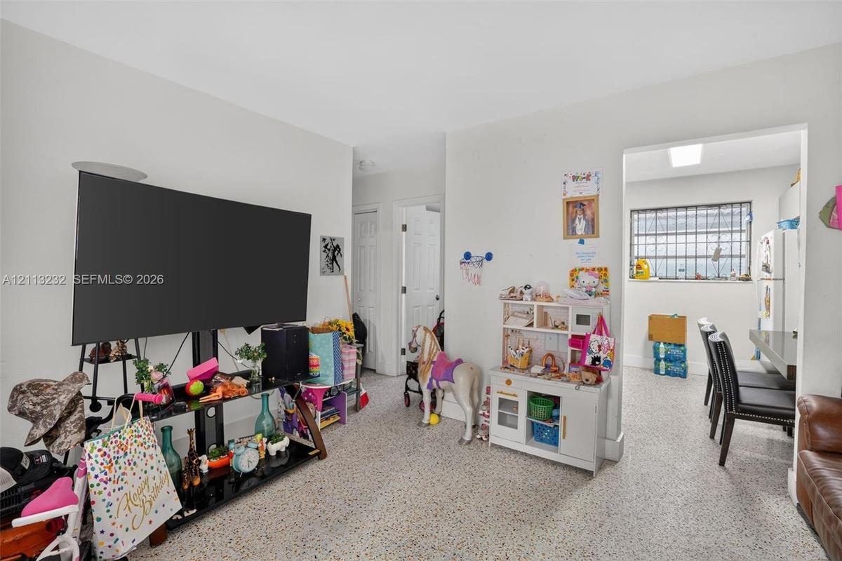 Neutral-toned interior space featuring terrazzo flooring, white interior doors, and a multi-pane window