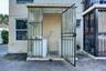 Exterior laundry area enclosed by corrugated polycarbonate panels and a metal security gate