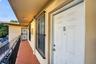 Exterior walkway with tiled flooring, metal railings, and unit entry door featuring protective iron security bars on window openings
