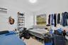 Room featuring white walls, terrazzo flooring, a window, and a wall-mounted air conditioning unit