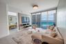 Living space featuring floor-to-ceiling glass sliding doors, custom wall-mounted media shelving, recessed ceiling lighting, and large-format tile floo