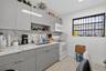 Kitchen featuring high-gloss gray cabinetry, stone-patterned countertops, a full-height stone-patterned backsplash, undermount stainless steel sink wi