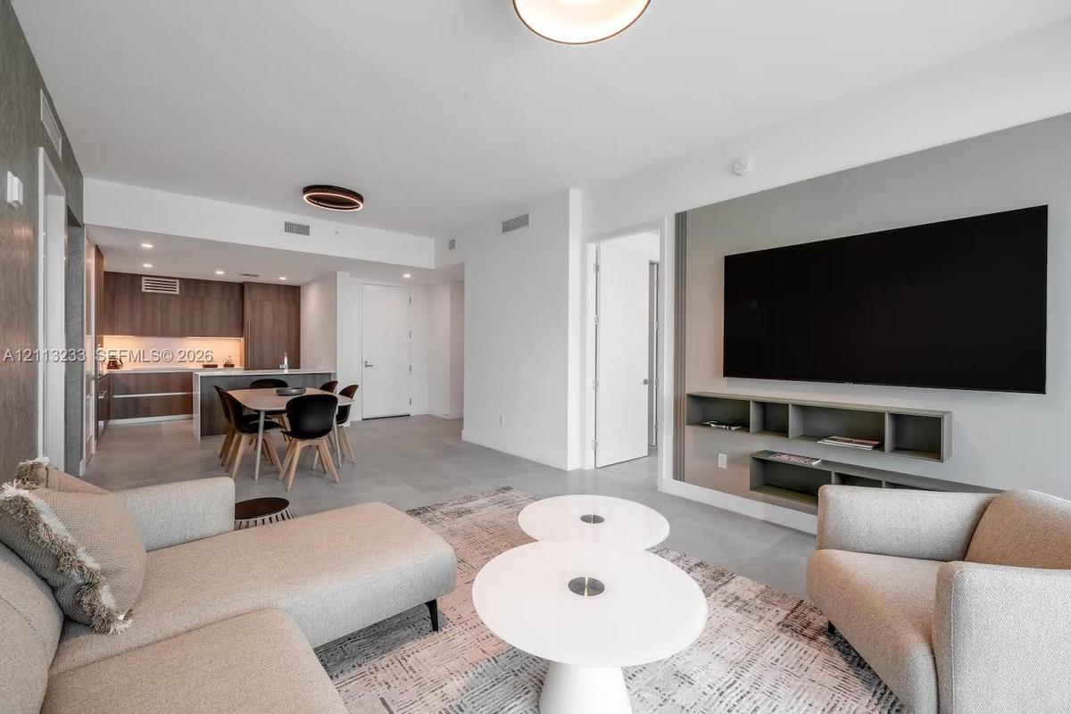 Open-concept interior featuring large-format tile flooring, recessed ceiling lighting, and a custom built-in media console