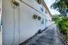 Exterior side elevation featuring a paved surface, concrete wall construction, and window-mounted HVAC units