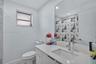 Bathroom featuring a vanity with a light-toned speckled countertop, an undermount rectangular sink, a chrome faucet, and a large-format vanity mirror 