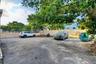 Asphalt parking area enclosed by a perimeter masonry wall and chain-link fencing, complemented by mature shade trees