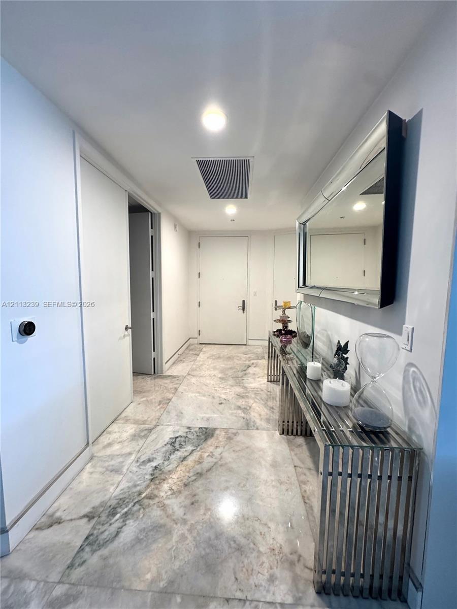 Foyer featuring large-format stone flooring, recessed lighting, and a solid-core door