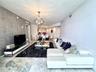Living space featuring polished stone flooring, textured accent wall, and a spherical multi-light chandelier