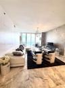 Living area featuring floor-to-ceiling glass paneling, stone tile flooring, a textured feature wall, and a contemporary spherical pendant light fixtur