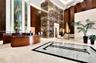 Grand lobby entrance featuring high-contrast stone flooring, a prominent full-height natural stone feature pillar, recessed cove lighting, and curved 