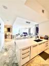 Kitchen island featuring white high-gloss cabinetry, a solid surface countertop, and an integrated undermount sink with a matte finish