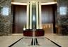 Grand entrance featuring floor-to-ceiling stone wall cladding, polished stone flooring with geometric inlay, and a built-in concierge desk