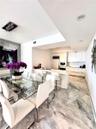 Kitchen featuring white cabinetry, solid-surface countertops, built-in appliances, and light-toned stone-finish flooring with geometric tile patterns