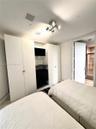 Built-in white cabinetry with integrated shelving and drawers, four-light modern ceiling fixture, and stone-finish flooring