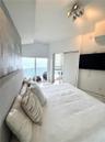 Textured feature wall with metallic finish, floor-to-ceiling glass sliding door, balcony access, and geometric ceiling-mounted light fixture