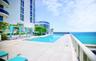 Outdoor swimming pool featuring a concrete sun deck, integrated steps, and metallic railings, set against an ocean backdrop