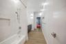 Bathroom featuring a soaking tub with integrated shower head, tiled wall surround with built-in niche, wood-finish flooring, floating dual-drawer vani