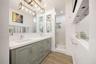 Dual-sink vanity with light gray shaker-style cabinetry, white solid-surface countertop, rectangular undermount sinks, and polished chrome fixtures, c