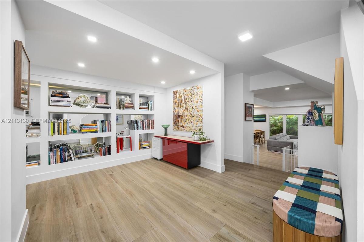 Interior space featuring wood-finish flooring, recessed lighting, and expansive built-in wall shelving with display niches