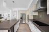 Kitchen featuring wood-finish flooring, solid-surface countertops, stainless steel appliances, a built-in double oven, and pendant lighting