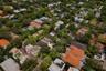 Aerial perspective showcasing a residential property with a hip roof, integrated hardscaping, and surrounding mature tree canopy