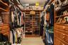 Custom wood-finish cabinetry featuring built-in shelving, multiple hanging rods, and integrated storage drawers