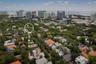 Aerial perspective of a residential lot featuring mature tree canopy, dense urban landscaping, and proximity to the coastline