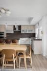 Kitchen featuring two-tone cabinetry with frosted-glass upper doors, dark solid-surface countertops, built-in stainless steel double wall oven, stainl