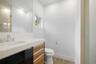 Wall-mounted mirror, vanity with wood-finish cabinetry and light-toned countertop, integrated basin, chrome-finish faucet, and wood-finish flooring