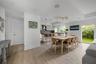 Open-concept interior featuring light wood-finish flooring, kitchen island with stone countertop, recessed ceiling speakers, modern multi-globe chande