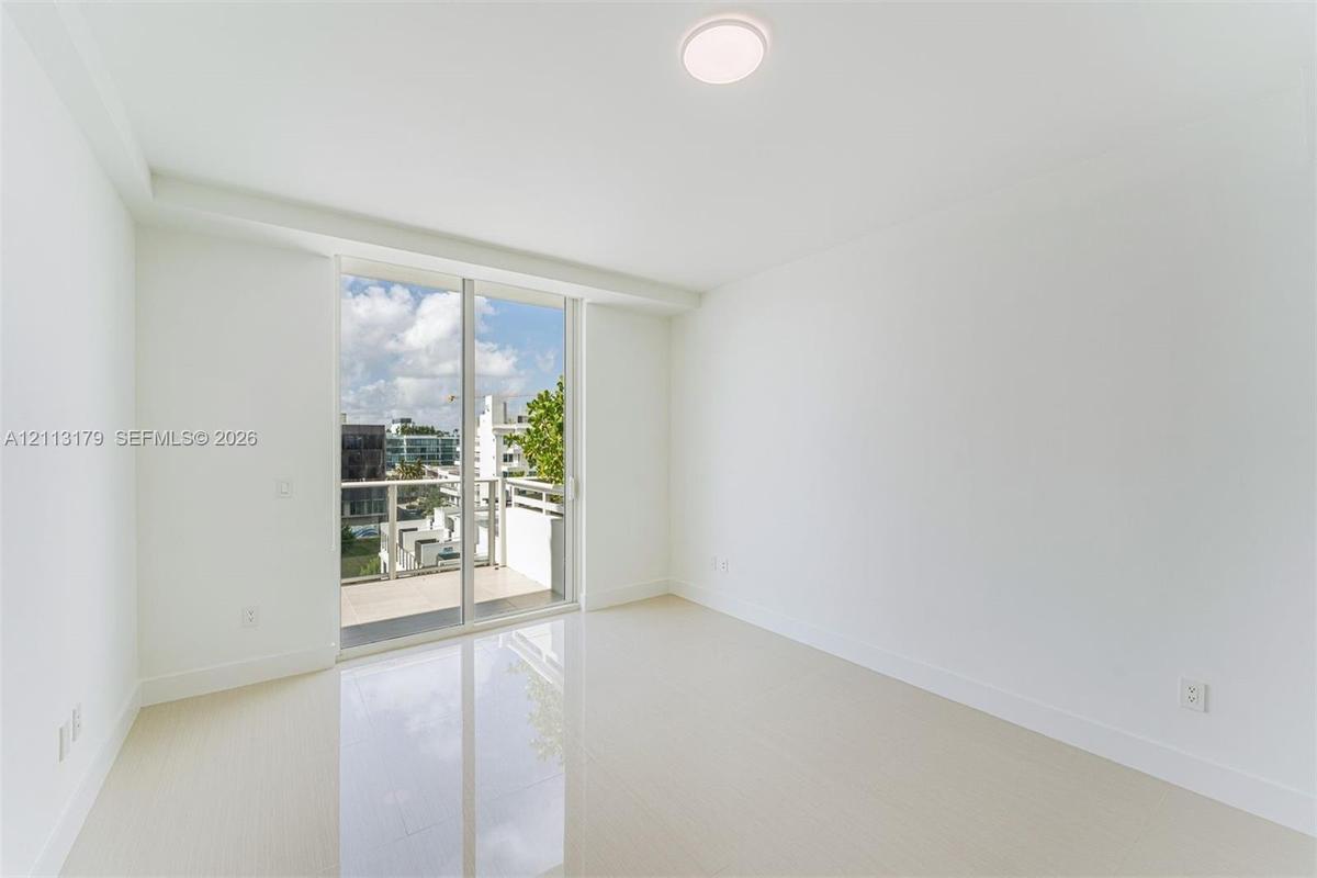 Room featuring large-format light-toned flooring, expansive glass sliding doors, and a private balcony