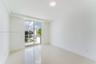 Room featuring large-format light-toned flooring, expansive glass sliding doors, and a private balcony