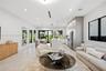 Open-concept interior featuring large-format tile flooring, recessed ceiling lighting, custom flat-panel cabinetry, a central kitchen island with wate