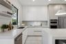 Modern kitchen featuring flat-panel cabinetry, light-toned stone countertops, built-in stainless steel appliances, dual open floating shelves, and an 
