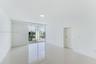 Open-concept room featuring light-toned tile flooring, recessed ceiling lighting, and sliding glass doors with access to a glass-railed balcony
