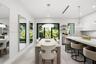 Modern kitchen featuring flat-panel cabinetry, a quartz waterfall island, large-format tile flooring, integrated linear lighting, and floor-to-ceiling