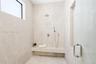Walk-in shower featuring floor-to-ceiling stone-finish tile, a built-in stone bench, overhead rainfall showerhead, adjustable handheld shower wand, an