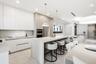 Kitchen featuring floor-to-ceiling cabinetry, a waterfall-edge center island, stone countertops, recessed lighting, and stainless steel built-in doubl