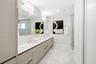 Extended floating vanity with dual undermount sinks, quartz countertop, full-width mirror, and walk-in shower with glass enclosure