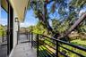 Covered balcony featuring matte black metal railings, concrete flooring, and wall-mounted exterior lighting