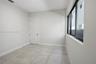 Room featuring large-format ceramic tile flooring, neutral wall paint, and a multi-pane window with dark frames