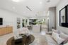 Open-concept living space featuring a central kitchen island with stone-finish waterfall countertop, large-format tile flooring, recessed ceiling ligh